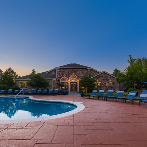 The outdoor pool and clubhouse entrance at Whisper Creek apartments in Lakewood, CO at twilight.